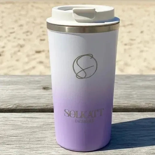 Lilac stainless steel travel mug on beach — stylish reusable coffee cup perfect for coastal mornings.