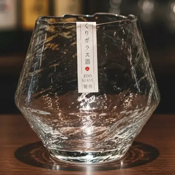 Crystal snowflake whisky tumbler catching natural light on a wooden bar.