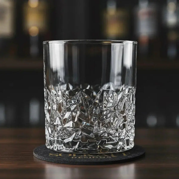Frosted whisky glass paired with a drink coaster on a bar, combining style and function.