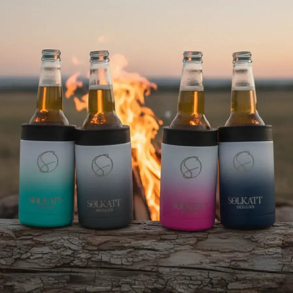 Four ombre insulated stubby coolers on a log in front of a campfire - Solkatt Designs