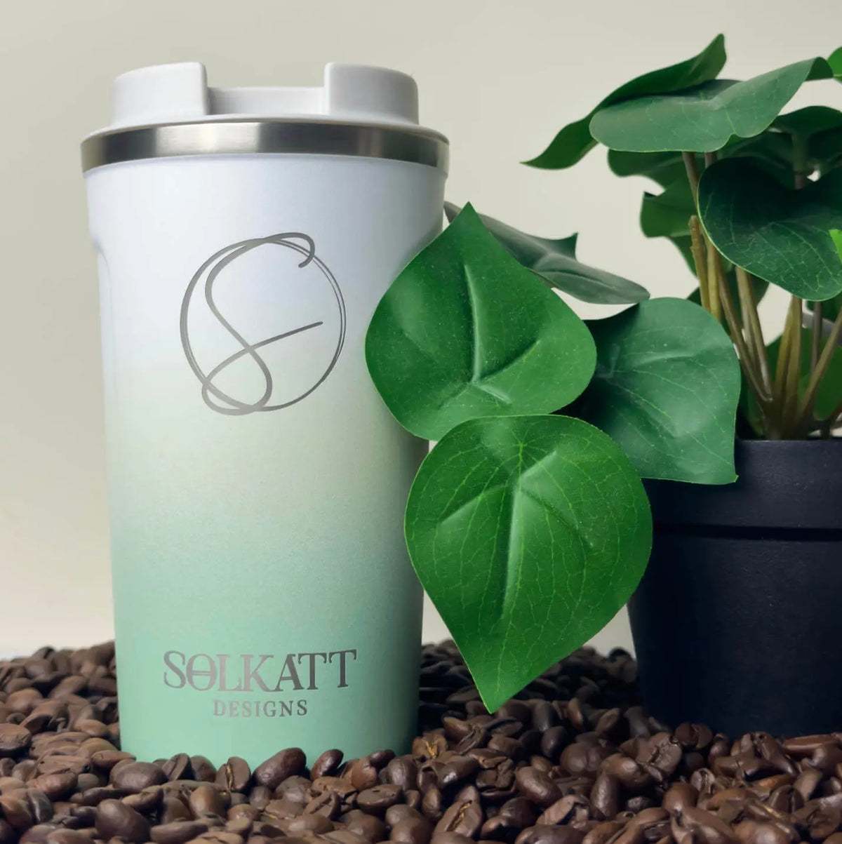 Pastel Green reusable coffee cup on coffee beans – stainless steel travel mug with lid – Solkatt Designs