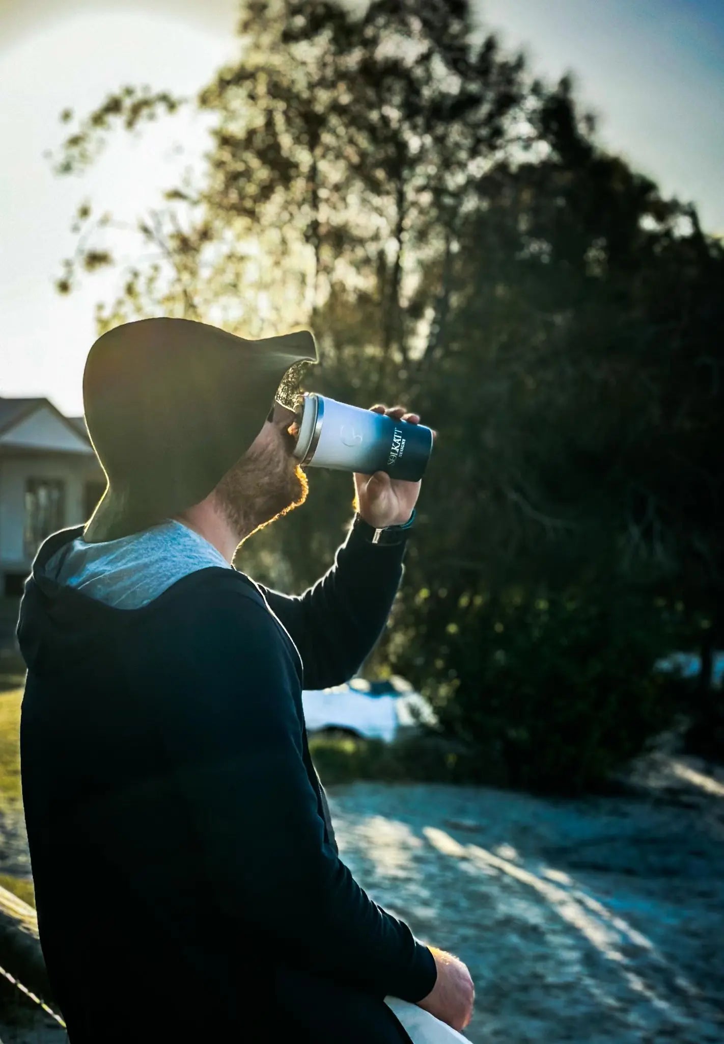 Man drinking from a reusable coffee cup outdoors on a cold morning