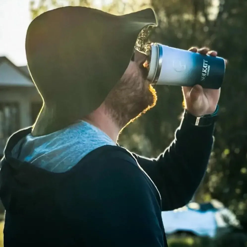 Man drinking from a reusable coffee cup outdoors on a cold morning