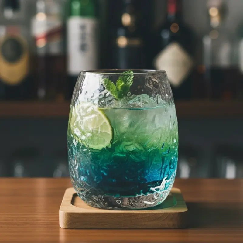Silkworm whisky glass holding a gin cocktail with citrus and herb garnish.