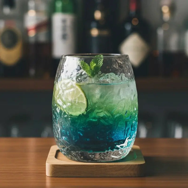 Silkworm whisky glass holding a gin cocktail with citrus and herb garnish.