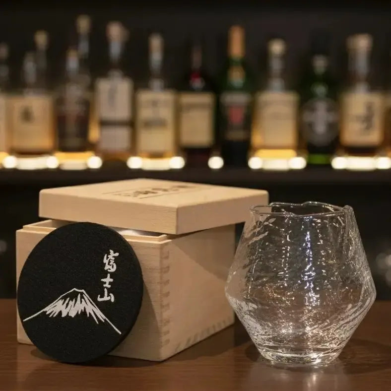 Snowflake whisky glass beside its wooden gift box packaging.