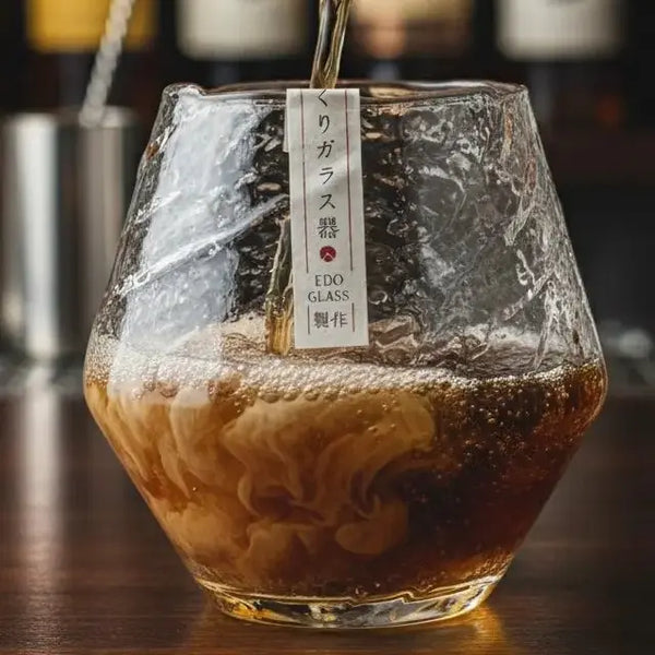 Snowflake whisky tumbler with ice cubes and dark rum swirling inside.