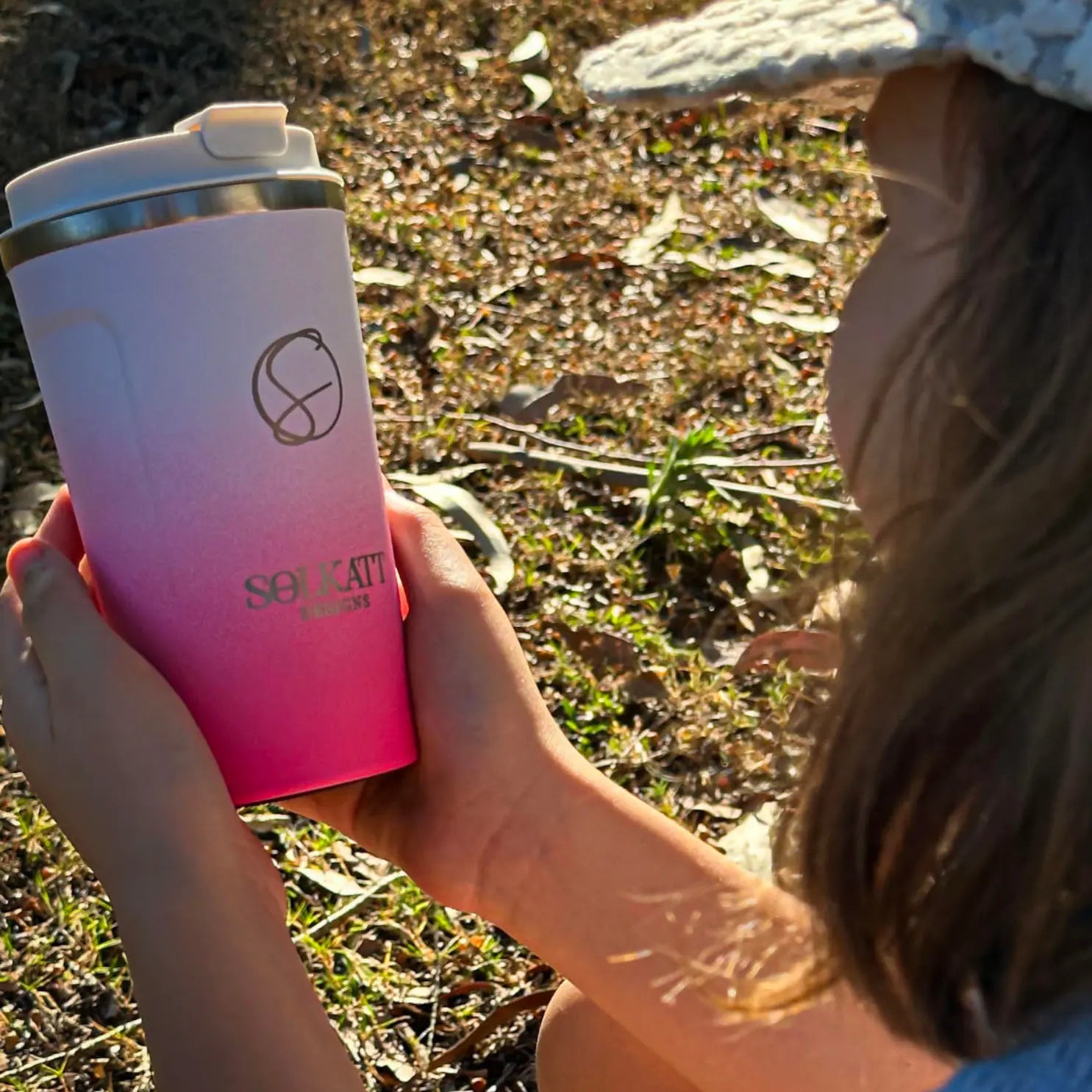 A person holding a solkatt designs reusable coffee cup outdoors