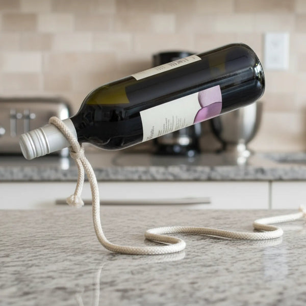 Nautical white rope wine bottle holder suspending a light rosé bottle on a bright kitchen counter, coastal kitchen design.